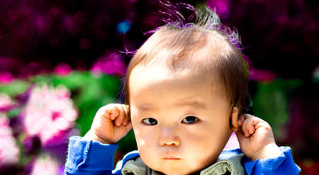 Baby touching his ears isolated on a black background and copy space and outdoors.? or hear no evilの写真素材