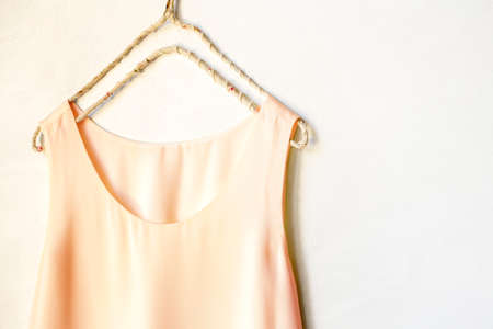 light pink tank top hanging on a hanger in a white wall. Close up and copy space.の写真素材