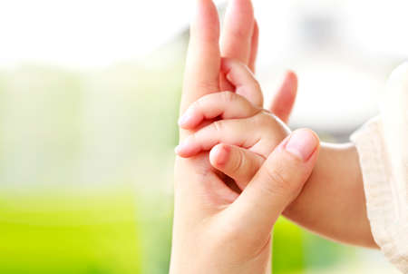 Family scene , close up parent and baby holding hands together and green and white background with copy space.の写真素材