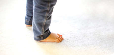 Child walking on carpet background in house. Child foot with jeans pants . close up and copy space.の写真素材