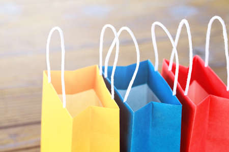 Colorful paper bags on the table on a wooden backgrounds and close up. red, blue, yellow.の写真素材