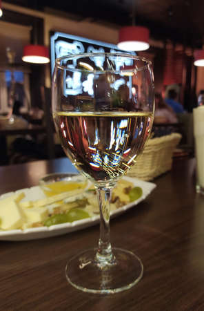The glare from the neon signs of the bar plays attractively in a glass of white wineの写真素材