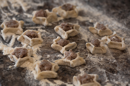 Raw homemade russian food - dumpling. Their in flower and have form of star. Pork, chicken mincemeat. Background table in kitchen.の写真素材