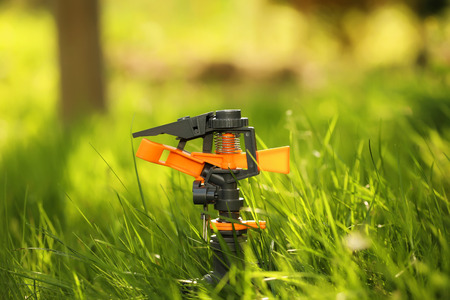 Plastic garden splinkter standing on the groud in the gazon grassの写真素材