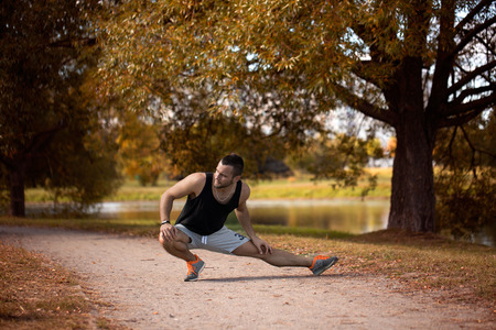 Energetic young man do exercises outdoors in park to keep their bodies in shape. Fitness concept....