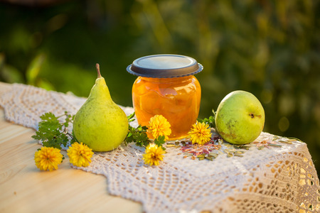 pear jam in jar and fresh pears on nature. Fresh sweet fruit delicacy. Agriculture concept. Food photo. Wooden background. Designers capture. Table with Welded yellow pears with flowersの写真素材
