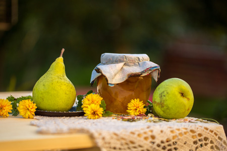 pear jam in jar and fresh pears on nature. Fresh sweet fruit delicacy. Agriculture concept. Food photo. Wooden background. Designers capture. Table with Welded yellow pears with flowersの写真素材