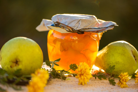 pear jam in jar and fresh pears on nature. Fresh sweet fruit delicacy. Agriculture concept. Food photo. Wooden background. Designers capture. Table with Welded yellow pears with flowersの写真素材