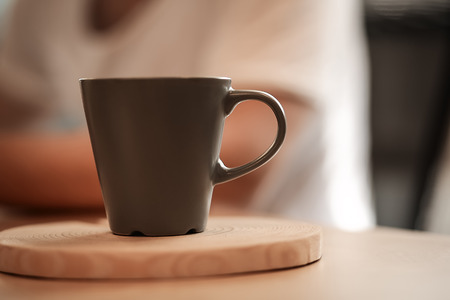 Brown dark cup of strong coffee or tea on wooden table desk in the ofice. Business background. Morning concept. Hot drink for wake up. Sunlight effect.の写真素材