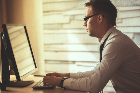 young man working from home on computer, manager at his workplace using technology, flare light.Male hands typing on laptop keyboard, businessman seated in office, businesspeople using modern devisesの写真素材