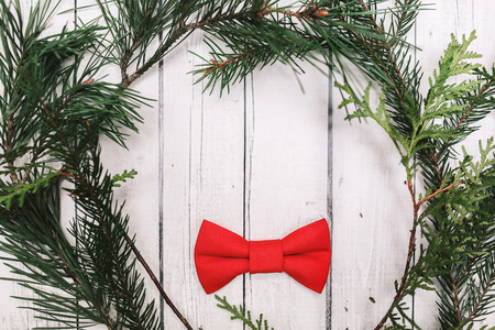 Christmas decoration in vintage toning on white wooden background with red bowtie and fir branch. Xmas decorative ornaments for design. Art work with texture for holiday new year 2017の写真素材
