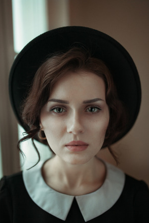 Close up fashion ifestyle portrait of beautiful girl in black in sunlight near the window. Modern split toning.の写真素材