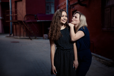 Beautiful blonde and brunette young women walking on the street. Flare for text and design. Lifestyle girls in the cityの写真素材