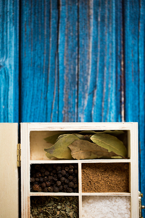 Spices in wooden box on blue background. Copy space for text and design. Food concept.の写真素材