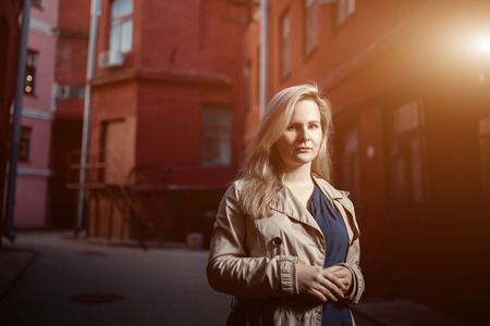 Beautiful blonde young woman walking on the street. Flare for text and design. Lifestyle girl in the cityの写真素材