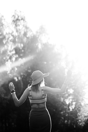 Silhouette of girl walking in park outdoor. Sunny summer lifestyle concept. Woman in dress and hat in field with dandelions. Light effect for text. Copyspace for design. BW photoの写真素材