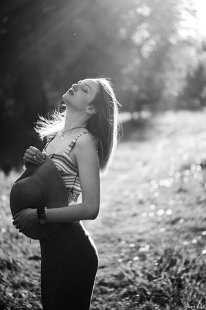Silhouette of girl walking in park outdoor. Sunny summer lifestyle concept. Woman in dress and hat in field with dandelions. Light effect for text. Copyspace for design. BW photoの写真素材