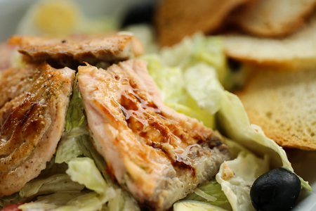 salad with salmon, freshness, Ruskson and black olives on white plate. Lifestyle healthy eating Food photo concept. Fried fish in focus.の写真素材