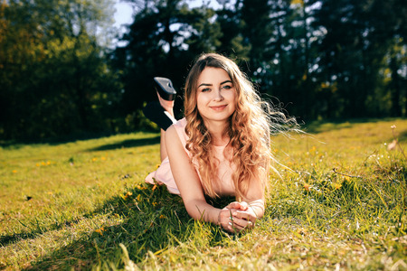 Happy girl lying on the grass and smyling. Attractive girl dreaming in summer timeの写真素材