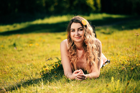 Happy girl lying on the grass and smyling. Attractive girl dreaming in summer timeの写真素材