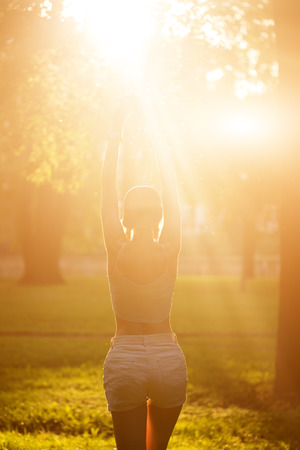 Silhouette of female model in sunlight in park. breathing fresh air outdoors. Healthy active lifestyle concept. portrait of happy sporty woman relaxing in park.の写真素材