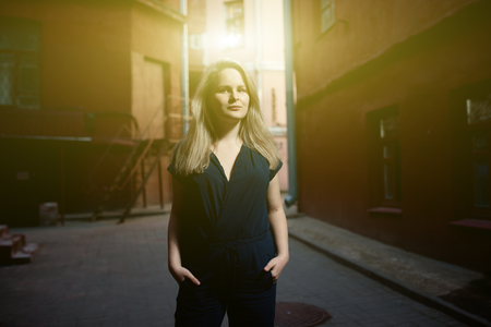 Beautiful brunette young woman wearing dress and walking on the street. Flare for text and design. Lifestyle in the cityの写真素材