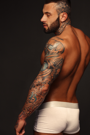 Sexy closeup portrait of handsome topless male model with beautiful eyes. Sexy man or muscular macho, bodybuilder, with muscle torso, body with six packs and abs poses on black background in white panties.の写真素材