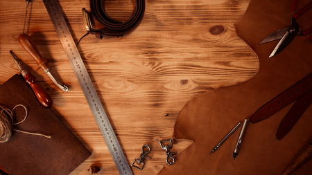 Leather craft. Tanners tools on grey wooden background top view. Copyspace.の写真素材