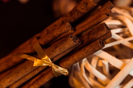 Ground cinnamon, cinnamon sticks, connected with a tray with a bow on a color background in a rustic style. Macro photo with selective focus. Close up food concept. Vintage toning. Retro style.の写真素材