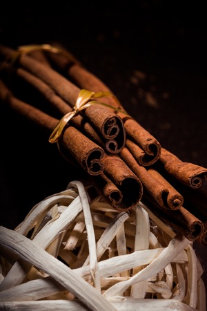 Ground cinnamon, cinnamon sticks, connected with a tray with a bow on a color background in a rustic style. Macro photo with selective focus. Close up food concept. Vintage toning. Retro style.の写真素材