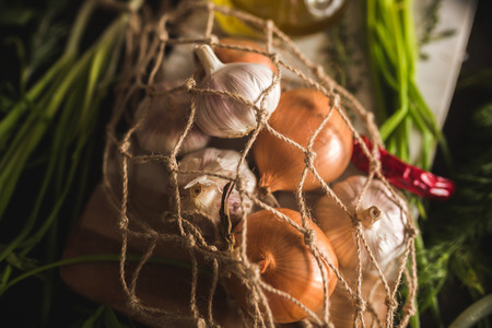 Raw Garlic, onion, dill and parsley for soup for dinner on the wooden table background. Rustic food styling. Natural ingredients for healthy recipe. Culinary book cover.の写真素材