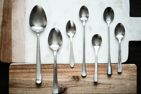 different spoons on stone marble wooden table background. Rustic vintage color toning.の写真素材