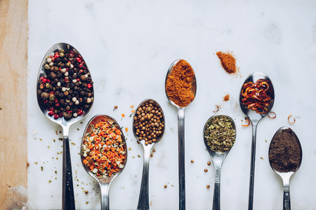 Spices in different spoons on stone marble table background. Rustic vintage color toning.の写真素材