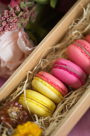 Row of cake macaroons in gift box on bright background. Close up macaron dessert on top view. Colorful almond cookies in pastel pink, yellow colors. Vintage style.の写真素材