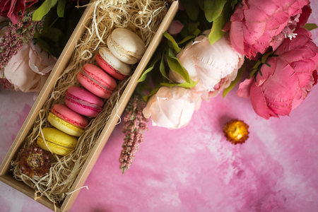 Row of cake macaroons in gift box on bright background. Close up macaron dessert on top view. Colorful almond cookies in pastel pink, yellow colors. Vintage style.の写真素材