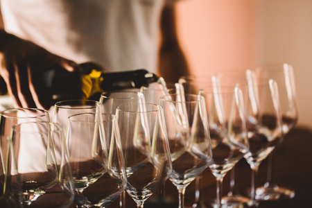 Bartender pours white wine in glasses on wooden bar counter. vineyard place with tasting.の写真素材