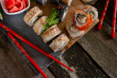 Sushi set food photo. Rolls served on brown wooden and slate plate. Close up and top view of sushi.の写真素材