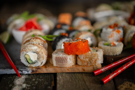 Sushi set food photo. Rolls served on brown wooden and slate plate. Close up of sushi.の写真素材