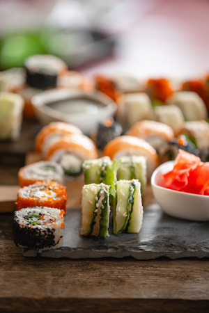 Sushi set food photo. Rolls served on brown wooden and slate plate. Close up of sushi.の写真素材