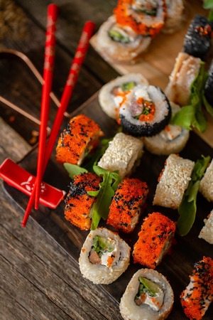 Sushi set food photo. Rolls served on brown wooden and slate plate. Close up and top view of sushi.の写真素材