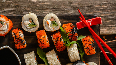 Sushi set food photo. Rolls served on brown wooden and slate plate. Close up and top view of sushi. 16 in 9 crop.の写真素材