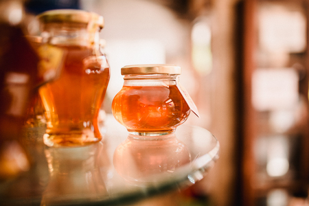 Close up food image of natural honey in little jar on shell on the market. Sunny warm trend toning photo,の写真素材