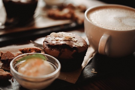 Close up food image of cup of coffee and dessert on the wooden table backgrouund in cafe. Trend warm toning. Photo with a small depth of field.の写真素材