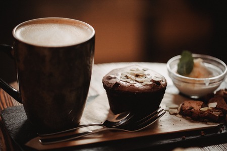 Close up food image of cup of coffee and dessert on the wooden table backgrouund in cafe. Trend warm toning. Photo with a small depth of field.の写真素材