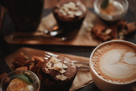 Close up food image of cup of coffee and dessert on the wooden table backgrouund in cafe. Trend warm toning. Photo with a small depth of field.の写真素材