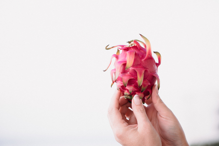 Close up food image of dragon fruit in woman's hand. Travel inspiration photo with a small depth of field. Blur background with copyspace for design.の写真素材