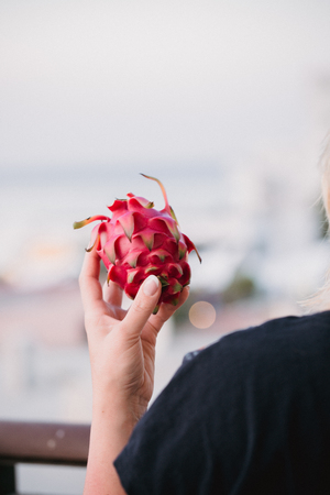 Close up food image of dragon fruit in woman's hand. Travel inspiration photo with a small depth of field. Blur background with copyspace for design.の写真素材