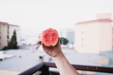 Close up food image of slised dragon fruit in woman's hand. Travel inspiration photo with a small depth of field. Blur background with copyspace for design.の写真素材