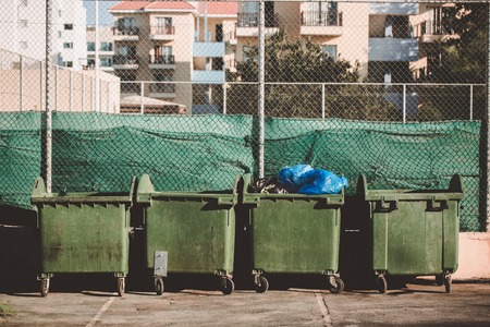 Ecology concept. Green metal trashcan with waste. Large plastic wheelie bins for rubbish, recycling and garden waste.の写真素材