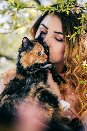 Girl and cat. Spring or summer warm weather concept. Bokeh background. Ginger kitten with two face color mask.の写真素材
